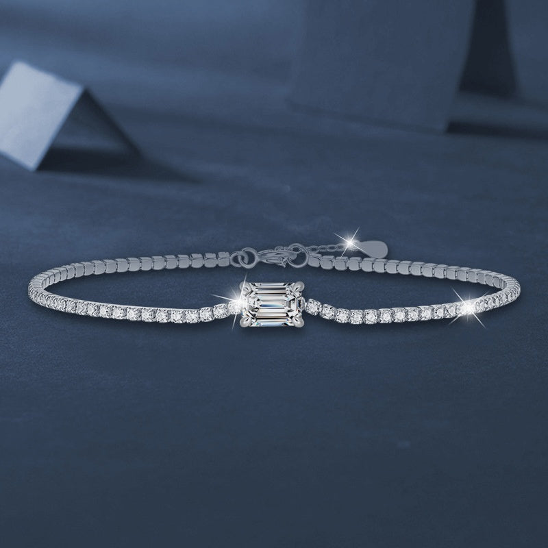 Bracelet Aurore Kouchta, ligne de moissanites pavé et pierre centrale taille émeraude sur fond bleu nuit
