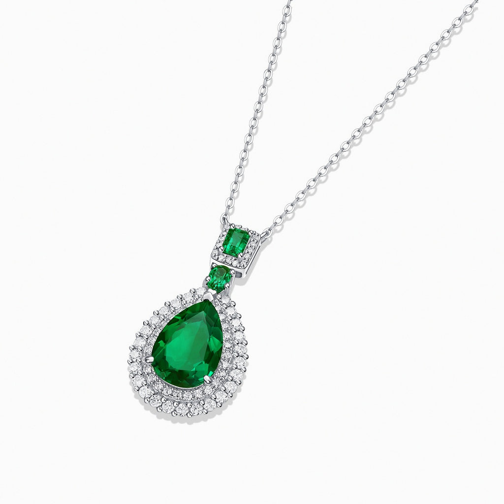 Collier goutte Kouchta en gros plan : émeraude de laboratoire taille poire, halos de moissanite